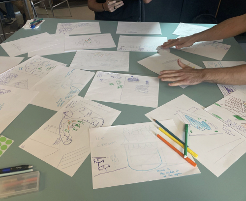 Team members spreading and discussing brainwriting sketches on a table